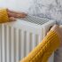 A person holds a heating radiator, demonstrating its size and design in a home setting.